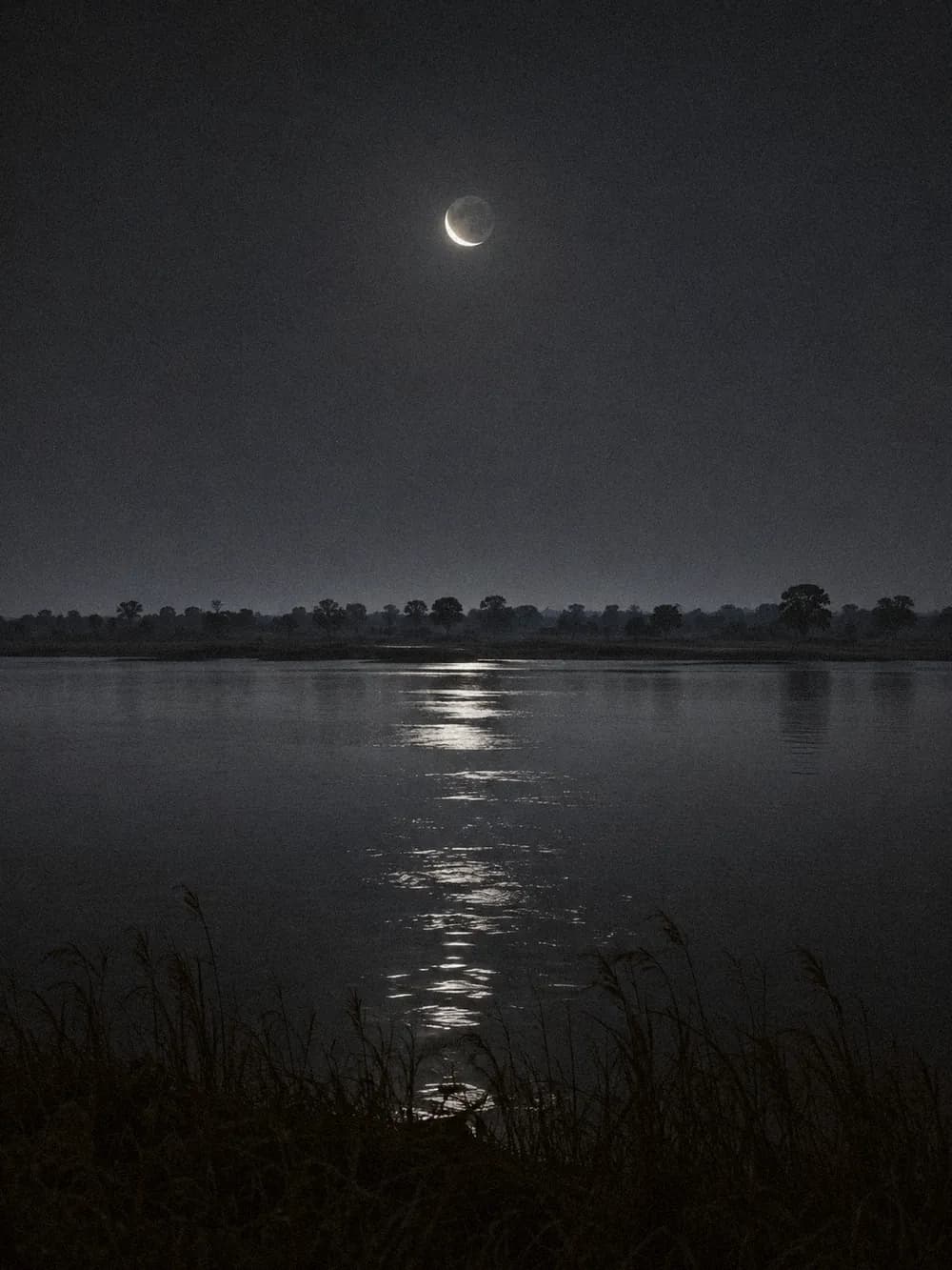 Crescent moon over still river
